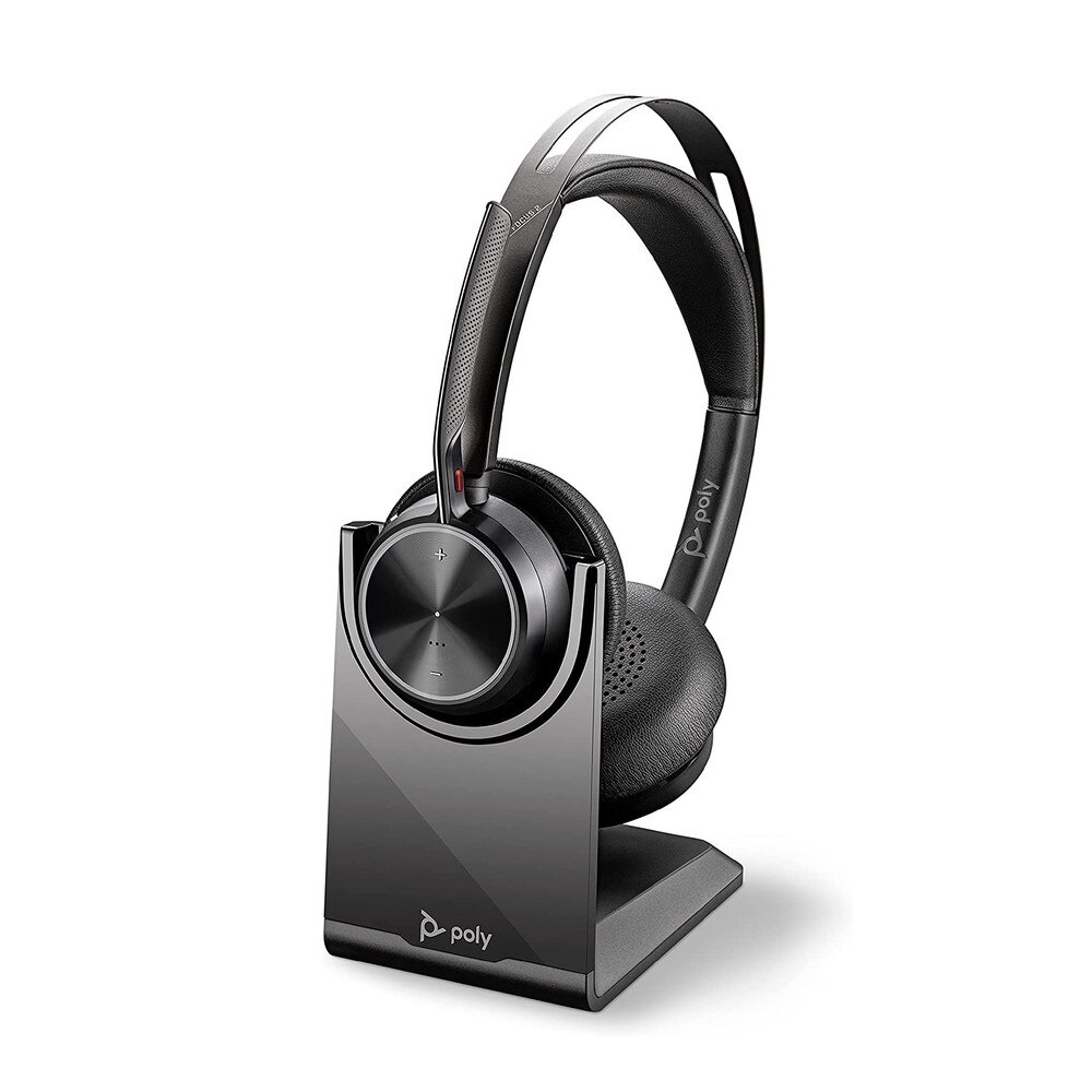 A photo of a Plantronics Voyager Focus 2 UC USB-C headset with a charging stand and a USB-C adapter.