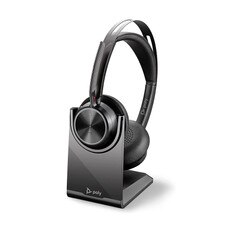 A photo of a Plantronics Voyager Focus 2 UC USB-C headset with a charging stand and a USB-C adapter.
