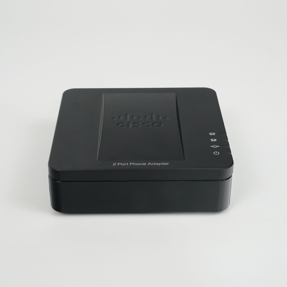 A black device with a curved shape and a Cisco logo on the front. The device has two phone ports, one Ethernet port, one Internet port, and a power connector on the back. The device also has four LED